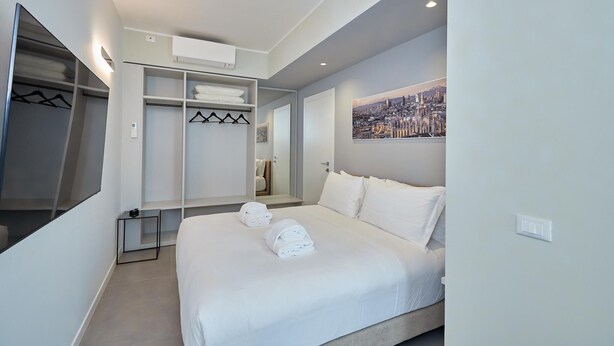 A modern hotel room with a large bed, a walk-in closet, and a cityscape painting on the wall. - Luxury apartment in the center of Milan - NEW (Milano)