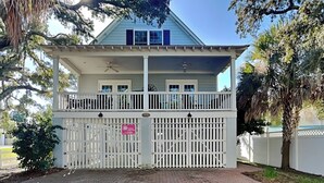 A two-story house with a covered porch and a gated entrance. - Spacious Tybee Retreat w/ Porch, Serene Setting Near Beach (Tybee Island)