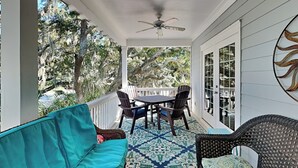 A covered porch with a table and chairs, a sofa, and a ceiling fan. - Spacious Tybee Retreat w/ Porch, Serene Setting Near Beach (Tybee Island)