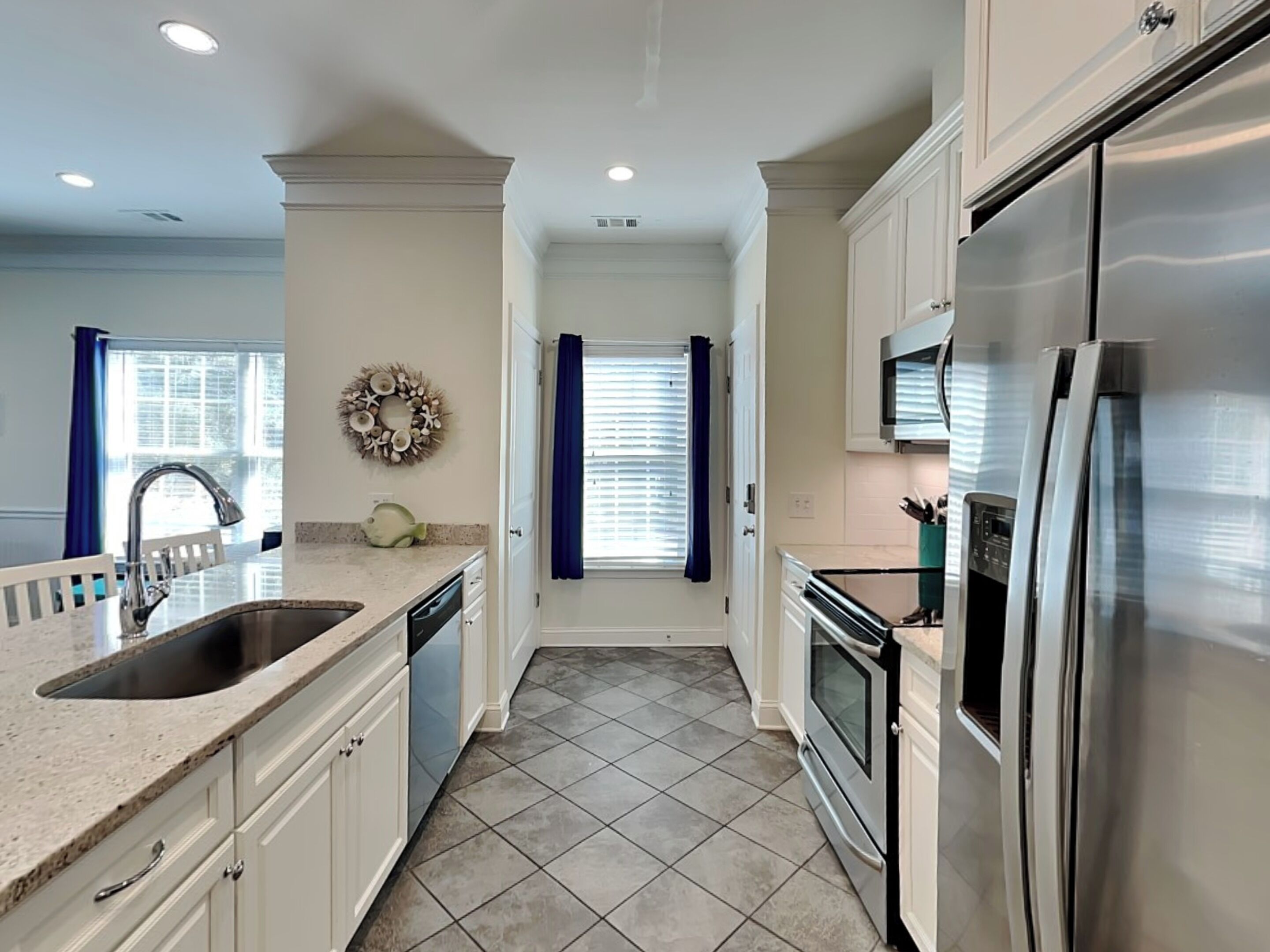 A modern kitchen with white cabinets, stainless steel appliances, and a granite countertop.