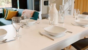 A dining table set with white plates, bowls, and clear wine glasses, with a white pitcher and a glass pitcher in the background. - Fawn Cottage Disabled Adapted 3 Bedroom hot tub (Alcester)