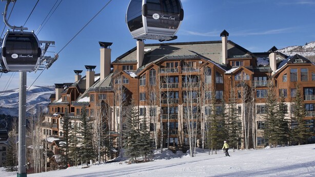 A ski resort with a cable lift, wooden buildings, and snow-covered ground.