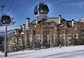 Une station de ski dotée d’un télécabine, de bâtiments en bois et d’un paysage enneigé.