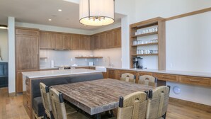 A modern kitchen with wooden cabinets, a central island, and a dining area with wicker chairs.