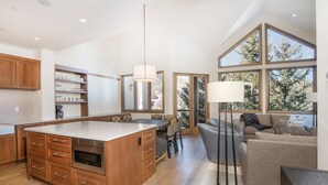 A spacious kitchen with a large island, wooden cabinets, and a dining area with a table and chairs.