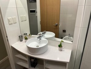 Une salle de bain moderne avec deux lavabos, un grand miroir et une porte en bois.