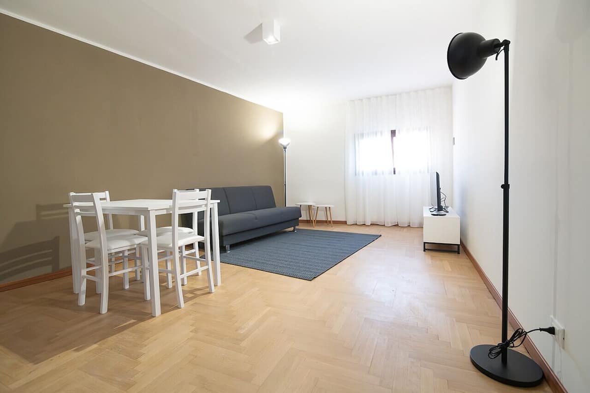 En stue med sofa, spisebord med stole, gulvlampe og et lille sofabord.