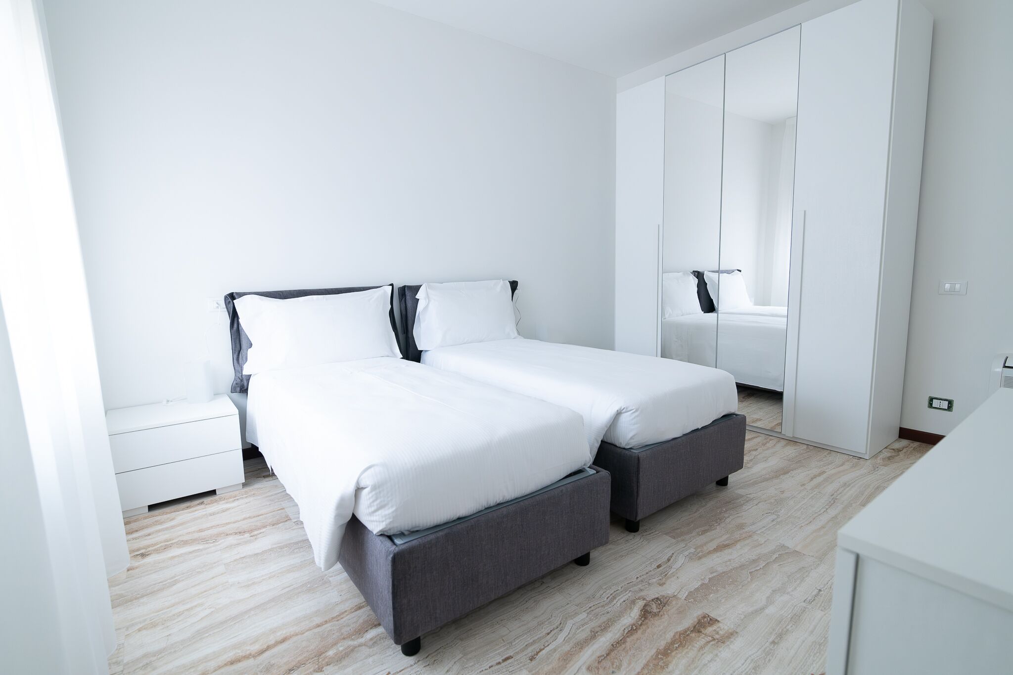 Un dormitorio moderno con cama, mesitas de noche y armario.
