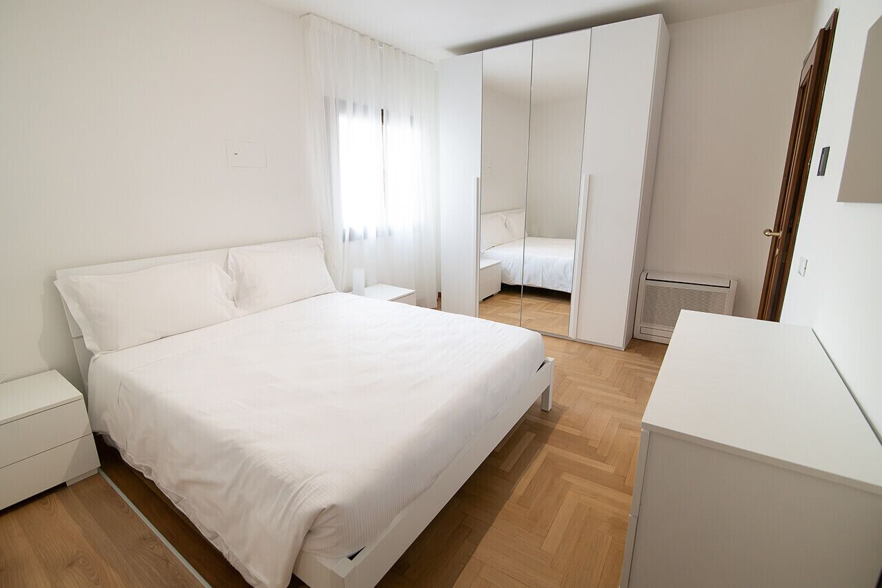 Une chambre à coucher comprenant un lit, une table de chevet, une armoire et un radiateur.