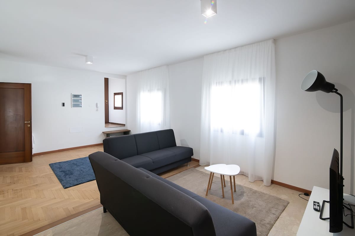 En moderne stue med sofa, lille bord, lampe og fjernsyn.