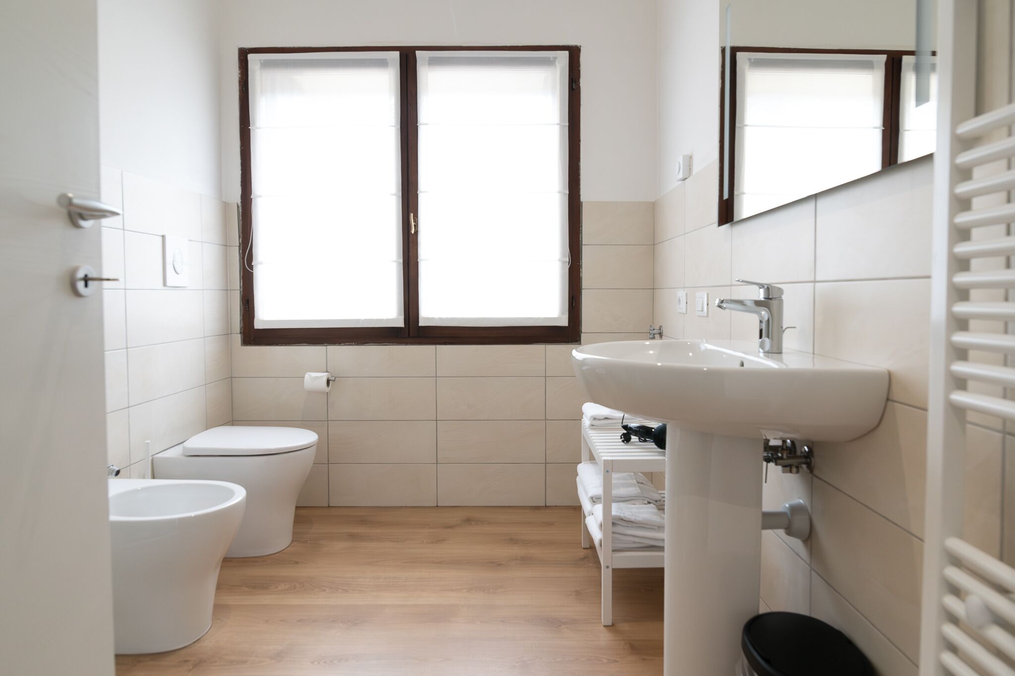 A bathroom with two toilets, a sink, a mirror, and a window.
