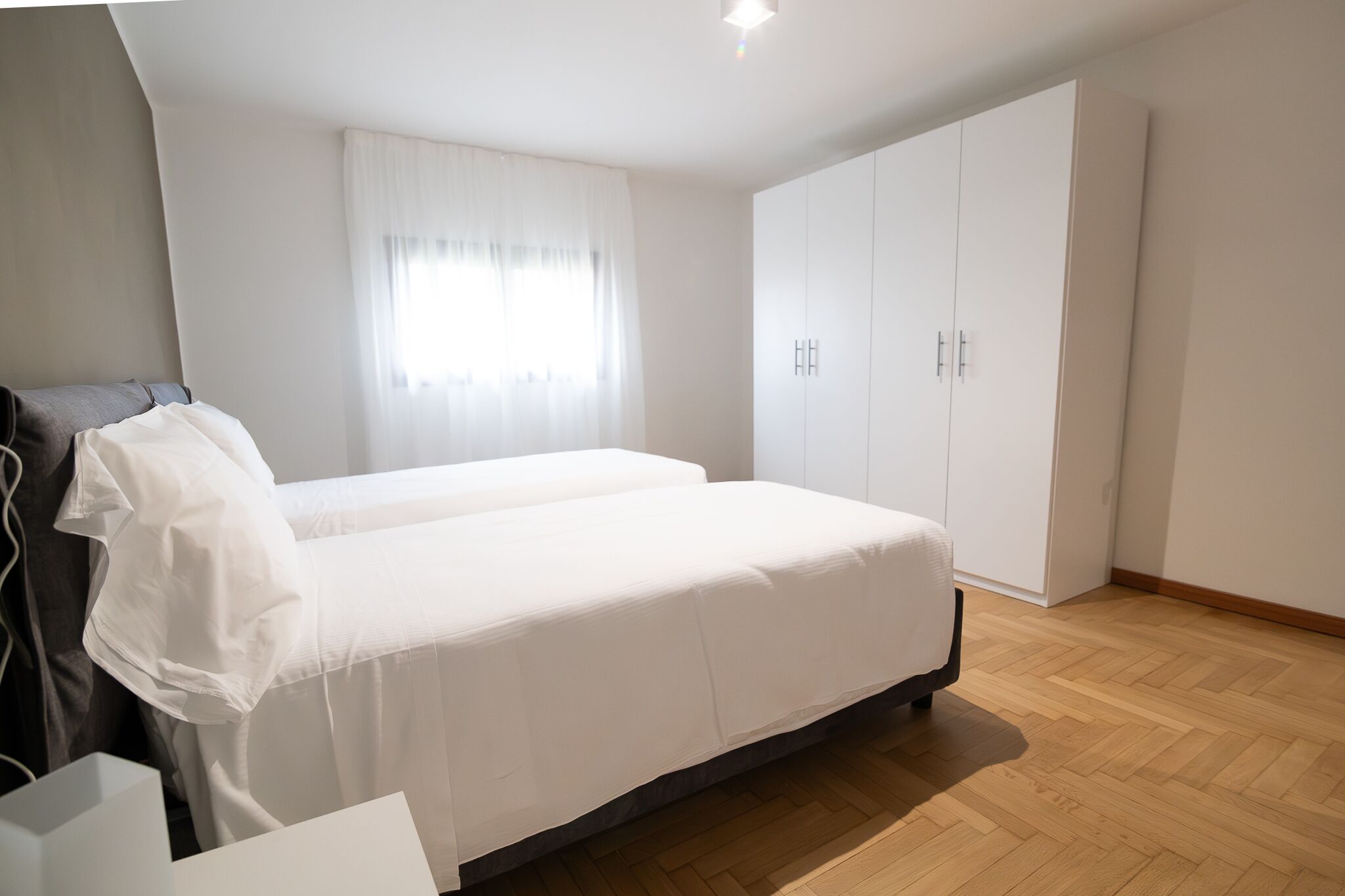 Ein Schlafzimmer mit Bett, Kleiderschrank und einem fenster mit Vorhängen.