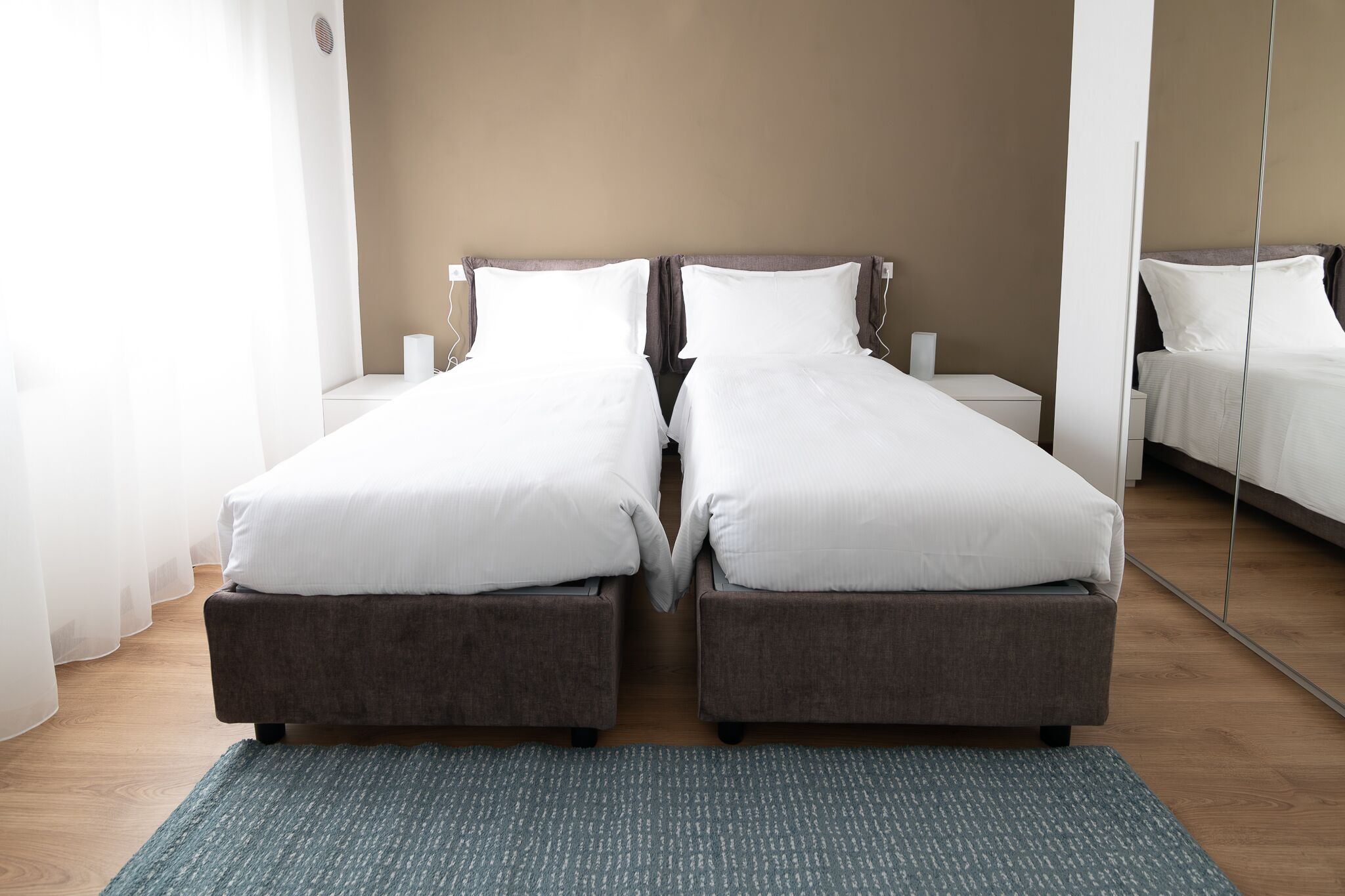 A twin room with two beds, a mirror, and a wooden floor.