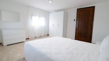 A bedroom with a bed, a dresser, a wardrobe, and a door.