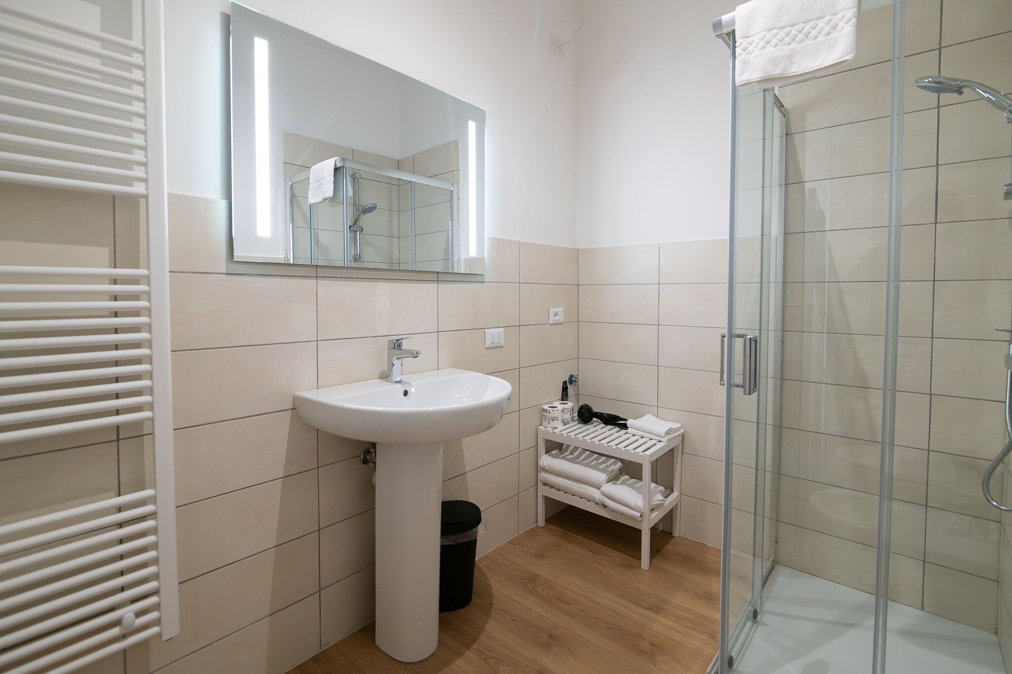 A modern bathroom with a white sink, mirror, and glass shower enclosure.