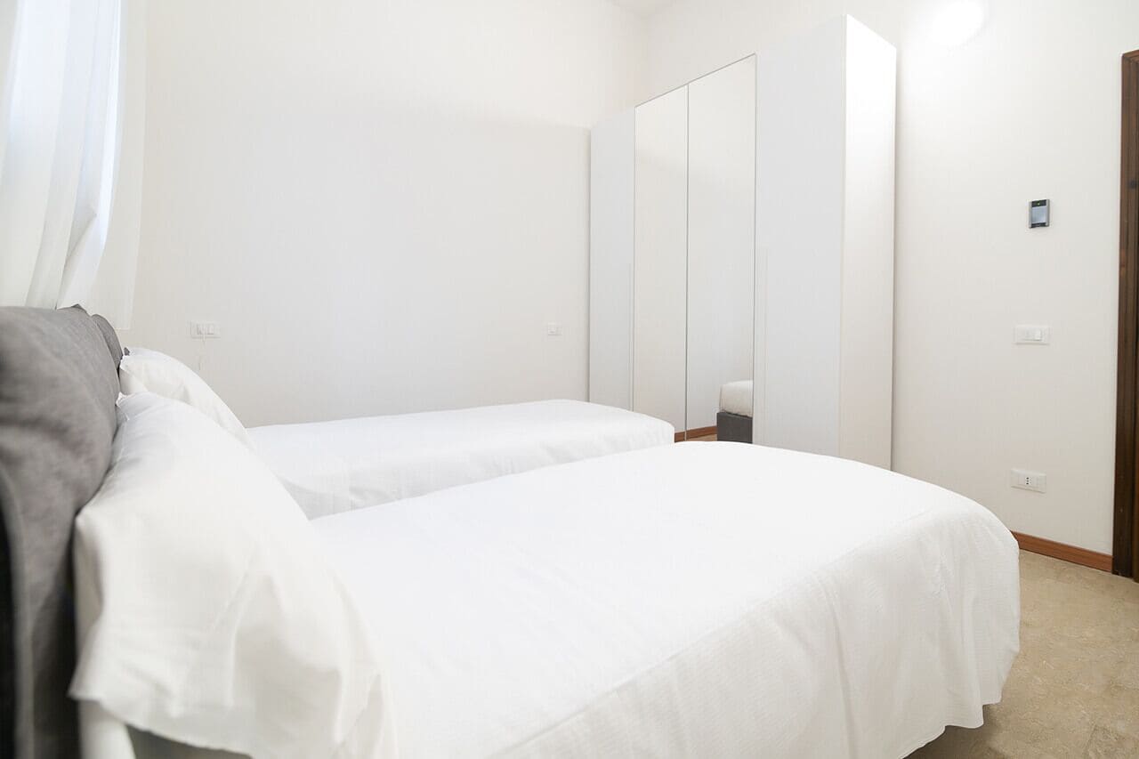 Un dormitorio con dos camas individuales, un armario y una mesita de noche.