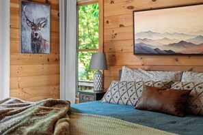 A wooden room with a bed, a painting of a deer, and a mountain landscape. - Unreal MTN Views • Secluded • Soak Dine Unwind (Epworth)