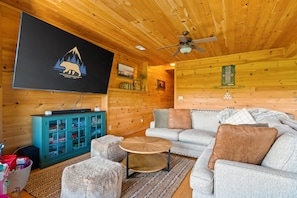 A cozy living room with a wooden ceiling, a mounted television, a green cabinet, a grey sofa, and a small round table. - Unreal MTN Views • Secluded • Soak Dine Unwind (Epworth)