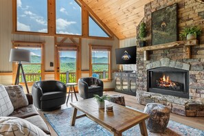 A cozy living room with a fireplace, comfortable seating, and large windows offering a view of the mountains. - Unreal MTN Views • Secluded • Soak Dine Unwind (Epworth)