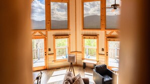 A spacious loft-style room with large windows, a ceiling fan, and a cozy seating area. - Unreal MTN Views • Secluded • Soak Dine Unwind (Epworth)
