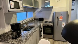 Eine kleine Küche mit Mikrowelle, Herd und Kühlschrank.