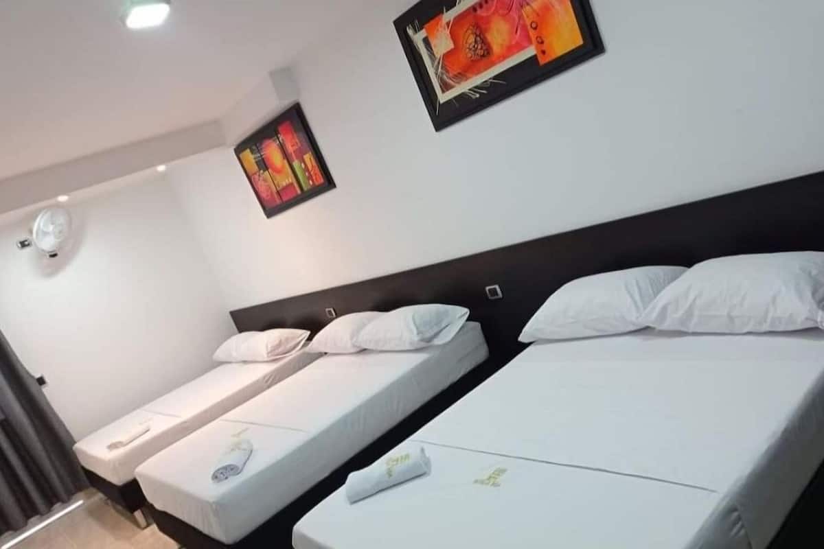 Une chambre d’hôtel avec deux lits simples, une tête de lit sombre et une horloge murale.