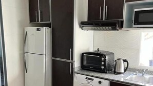 Cocina compacta con refrigerador, microondas, tostadora y lavadora.