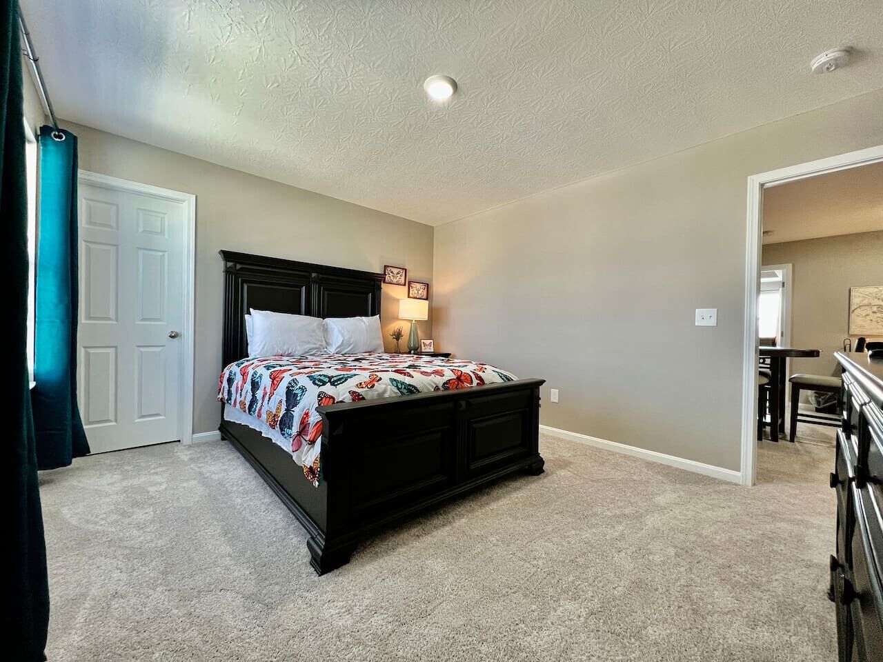 Quarto com cama, porta, parede e luminária no teto.