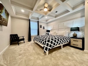 A bedroom with a bed, a chair, a nightstand, and a ceiling fan.