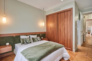 A hotel room with a large bed, wooden headboard, and a wardrobe. - Sublime apartment in the center of Paris (Paris)