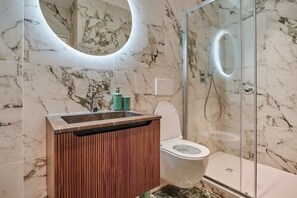 A modern bathroom with a marble wall, a wooden vanity, a toilet, and a glass shower enclosure. - Sublime apartment in the center of Paris (Paris)