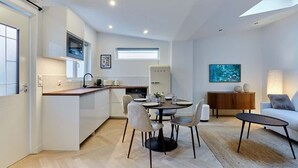 A modern kitchen with white cabinetry, a dining area with a round table and chairs, a sofa, and a lamp. - Superb apartment Arc de Triomphe (Paris)