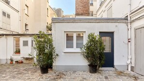 A courtyard with a small building, potted plants, and a cobblestone floor. - Superb apartment Arc de Triomphe (Paris)