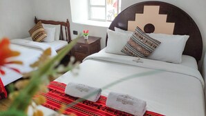 A hotel room with two beds, each with white linens and patterned pillows. There are two small wooden nightstands with lamps, and a window providing natural light. - Hostal Cusco Internacional (Cusco)