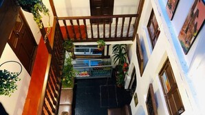 A narrow corridor with a wooden railing, potted plants, and a staircase leading to an upper level. - Hostal Cusco Internacional (Cusco)