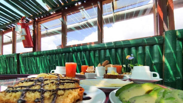 A table with breakfast items including a slice of cake, avocado, and juice. - Hostal Cusco Internacional (Cusco)