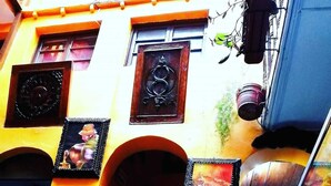 A building with a yellow facade, a wooden door, and a staircase leading to an entrance. - Hostal Cusco Internacional (Cusco)