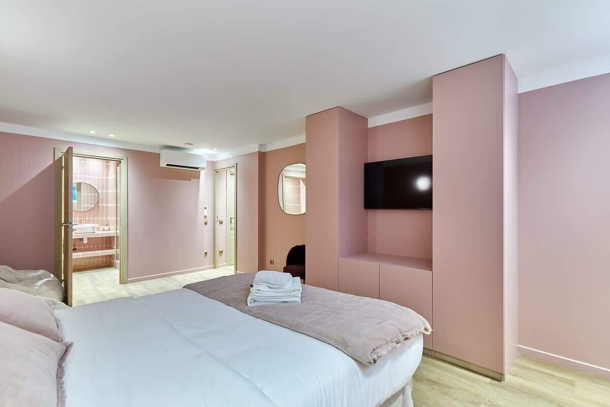 Une chambre d’hôtel avec deux lits, un téléviseur fixé au mur et une salle de bain visible à travers une porte ouverte.