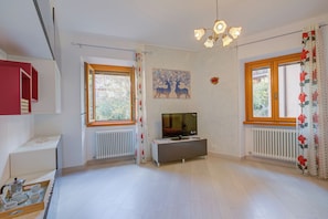 Enjoy a peaceful stay in this cozy room featuring a flat-screen TV, radiator, and seating area with a bench.