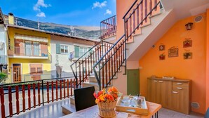A balcony with a wicker basket of flowers, a table with a book, and a staircase. - Casa dei Nonni (Arco)