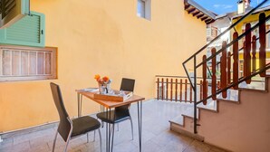 A balcony with a table and chairs, a window with shutters, and a staircase. - Casa dei Nonni (Arco)