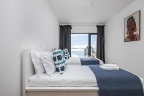 A modern hotel room with a large bed, a view of the sea, and a painting on the wall. - Casa Jos Ant nio A by Homie (Santa Cruz)