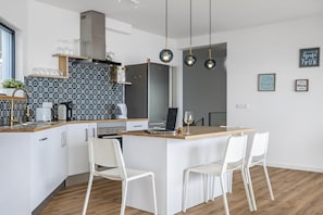 A modern kitchen with a central island, white chairs, and pendant lighting. - Casa Jos Ant nio A by Homie (Santa Cruz)