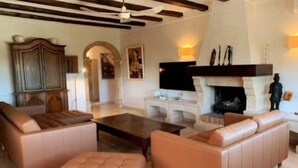 A spacious living room with leather sofas, a fireplace, and a television. - 12 Persoons luxe villa in Javea. Heated pool! (Jávea)