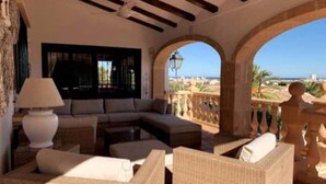 A cozy living room with a sofa, armchairs, and a lamp. It features an arched balcony with a view of the sea. - 12 Persoons luxe villa in Javea. Heated pool! (Jávea)