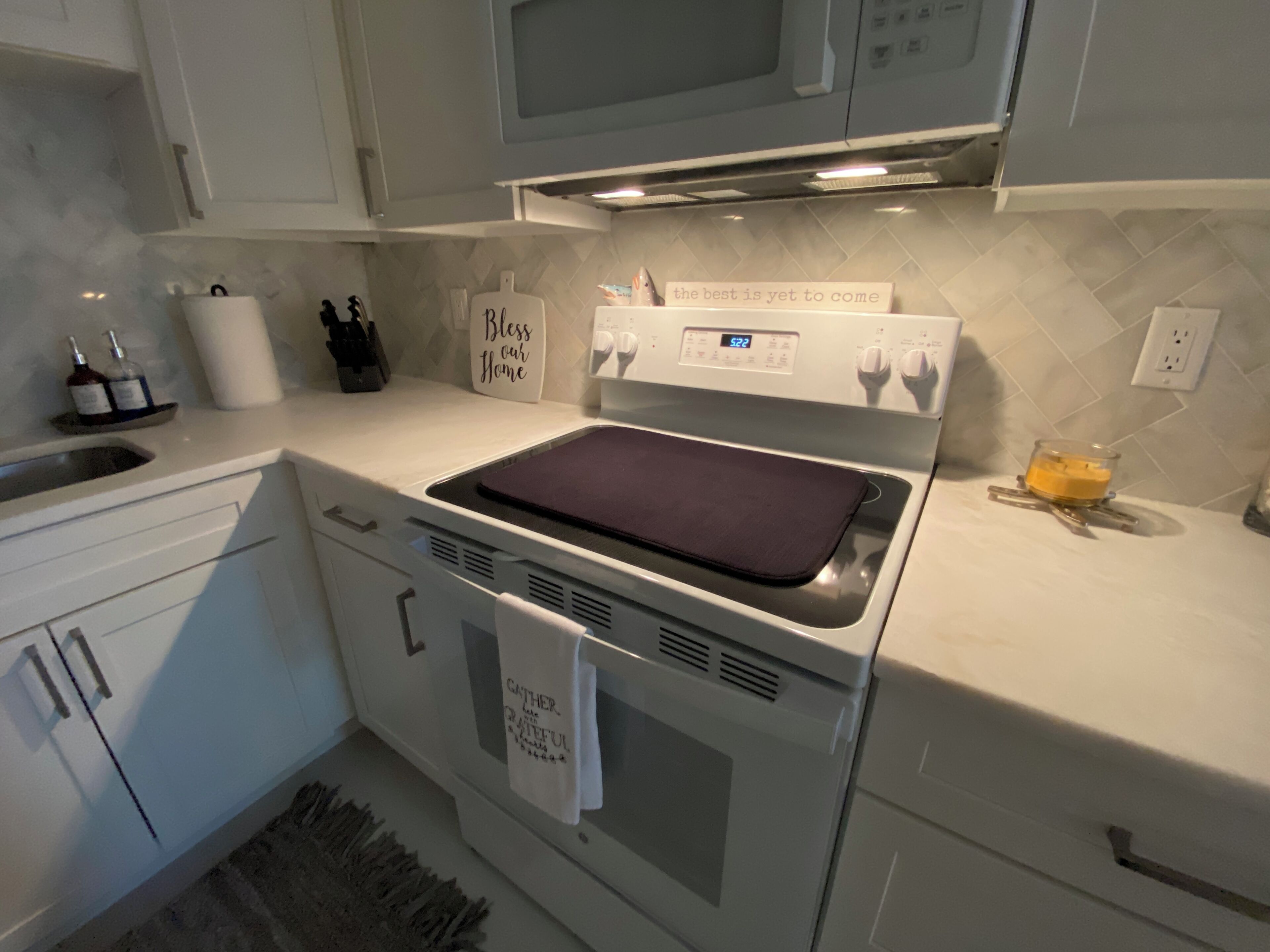 Een moderne keuken met witte kastjes, een ingebouwde magnetron, een oven en een roestvrijstalen kookplaat.