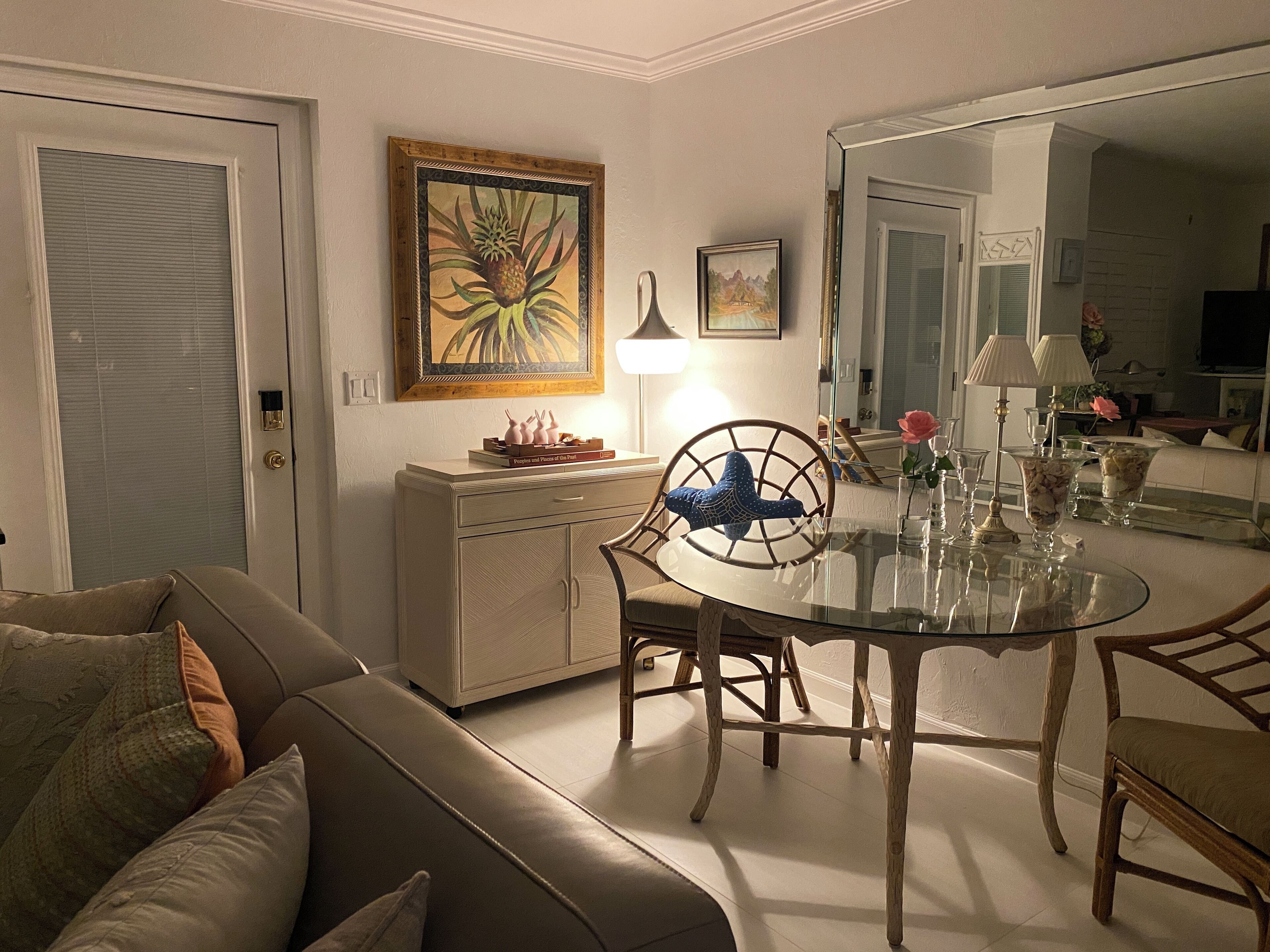 A living room with a glass dining table, a sofa, a cabinet, and a door.