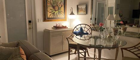 A living room with a glass dining table, a sofa, a cabinet, and a door.