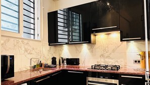 A modern kitchen with black cabinets, a built-in oven, a microwave, and a washing machine.