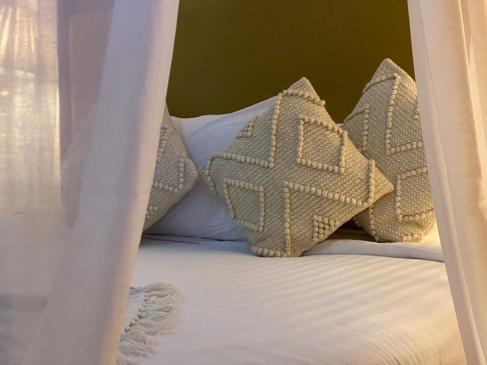 A bed with white bedding and decorative pillows.